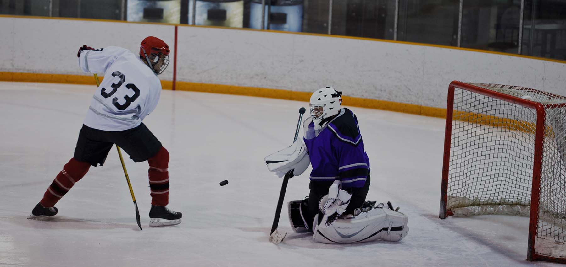 An ice hockey player takes a shot at a stopper
