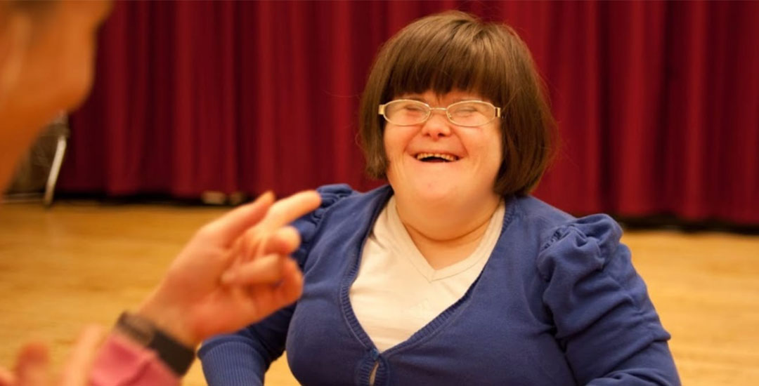 A young lady with Down syndrome smiles and laughs
